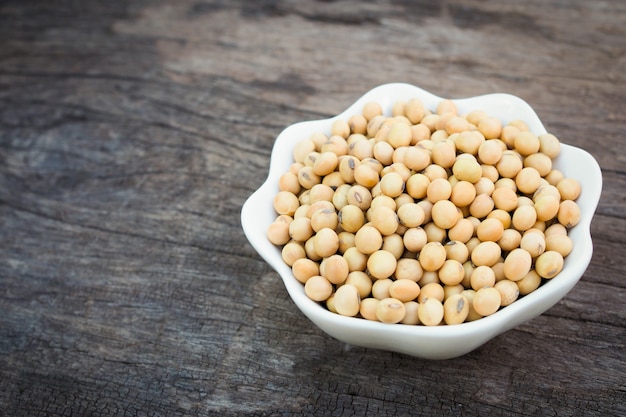 Soybeans in white bowl on old wooden background