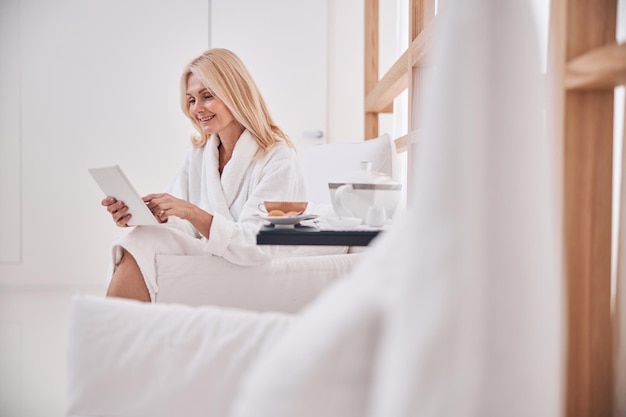 Spa client using her tablet computer in the armchair