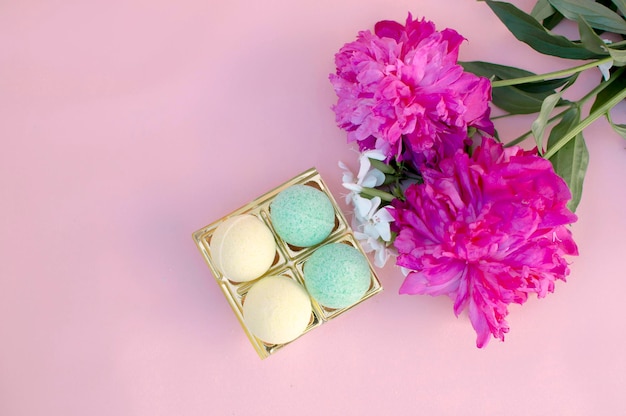 SPA composition with bath bombs and two peonies on a pink background Closeup Copy the space for the text The concept of therapy I'm taking a relaxing bathHomemade spa products