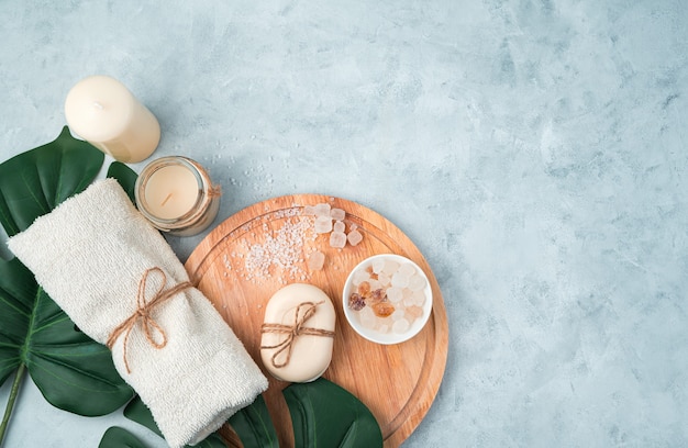 Spa composition with care products on a light blue background with tropical leaves.