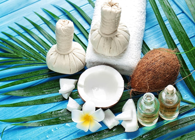 Spa composition with coconuts and palm leaf on wooden background