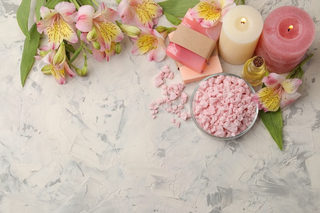 Spa composition with sea salt, aroma oils and handmade soap with flowers on grey and white concrete