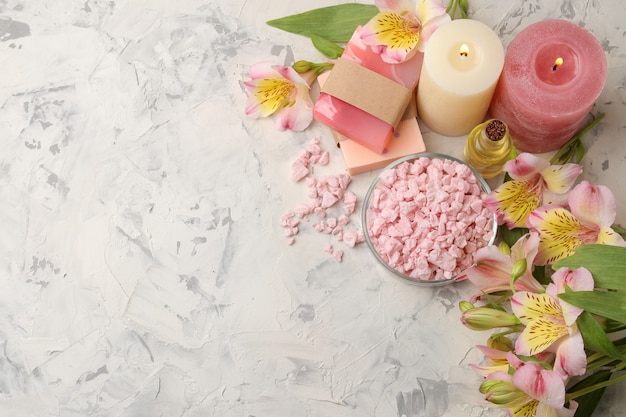 Spa composition with sea salt, aroma oils and handmade soap with flowers on grey and white concrete