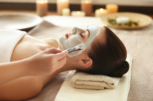 Spa concept. Hand applying nourishing mask on female face in spa salon