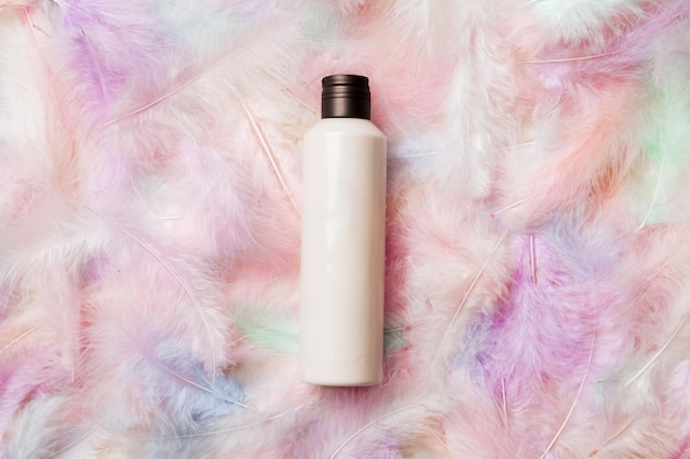 Spa cosmetic product cream bottle branding mock up top view with feathers background Flat lay