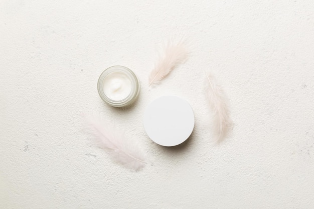 Spa cosmetic product cream jar branding mock up top view with feathers background Flat lay