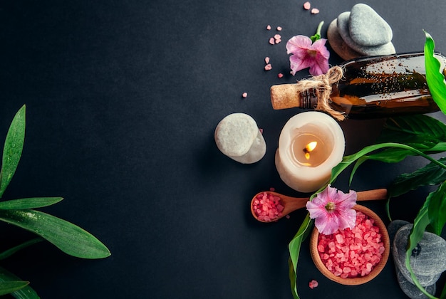 Spa essentials including candle salt stones oil and green leaves