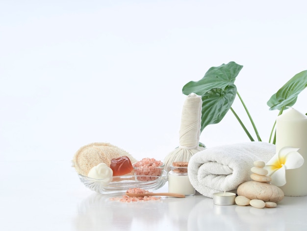 Spa massage concept, herbal compress ball, cream, flower soap, scented candle and Himalayan pink salt, isolated on white