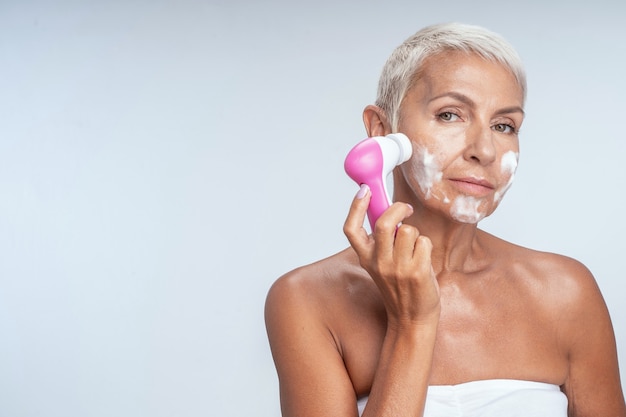 Spa procedures. Delighted female looking forward while doing morning procedure