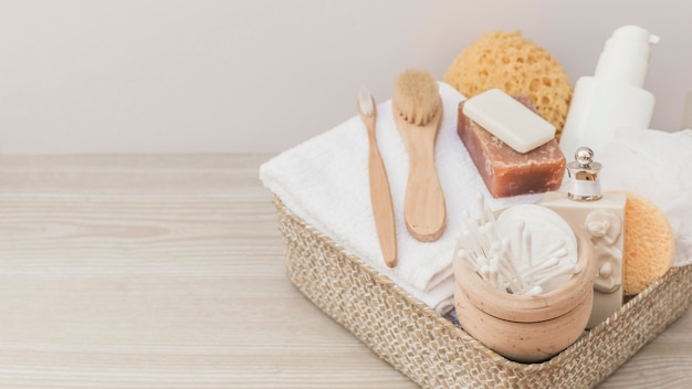 Spa products with brushes and loofah in tray on wooden backdrop