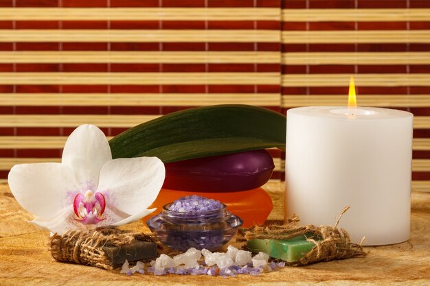 Photo spa products with orchid flower, bowl with sea salt, handmade soap, candle on wooden board