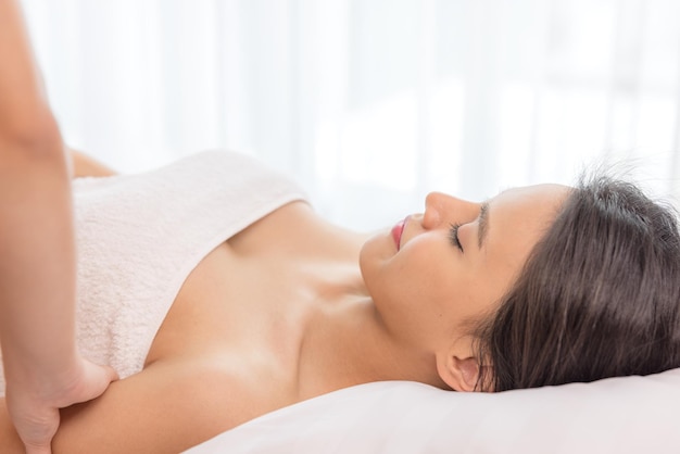 In a spa salon a young woman enjoys massage therapy