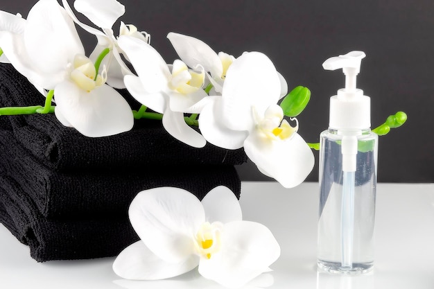 SPA setting with black bath towels and orchid flower and bottle spa concept