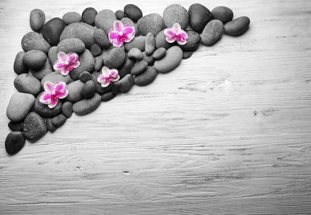 Photo spa stones and orchids on wooden background