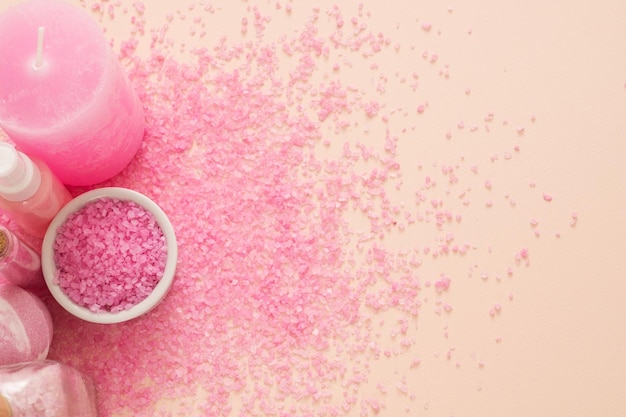 Spa therapy Mineral body care products Cropped top view of candle and pink bath salt on peach background