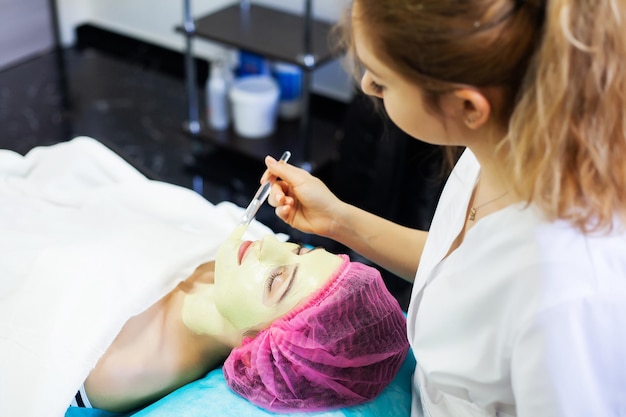 Spa therapy for young woman having facial mask at beauty salon.