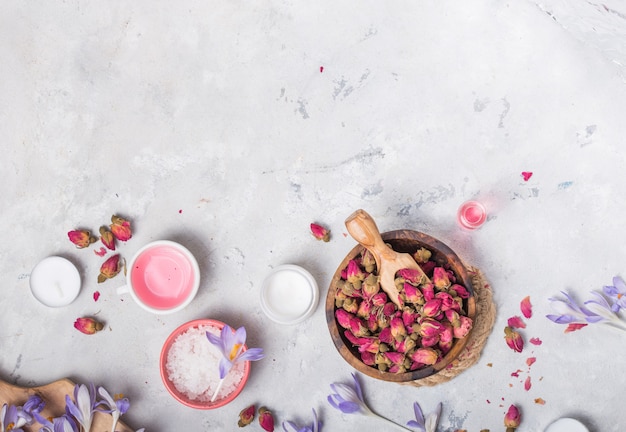 Spa and wellness concept with sea salt, dry roses, brush, oil and towel