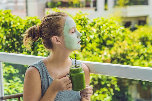 Spa Woman applying Facial green clay Mask. Beauty Treatments. Fresh green smoothie with banana and spinach with heart of sesame seeds. Love for a healthy raw food concept. Detox Concept