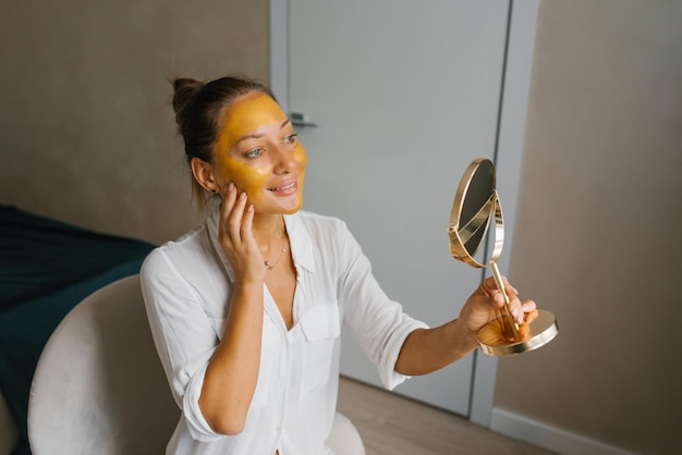 Spa woman puts a golden mask on her face Beauty treatments at home