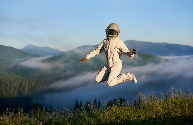 Space traveler jumping in the air in mountains