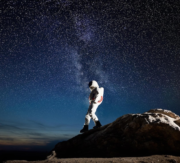 Space traveler walking down the mountain under starry sky