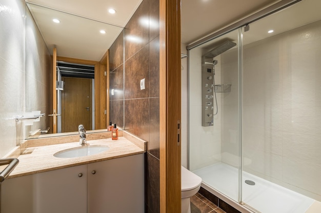 Spacious bathroom with separate toilet area and an electronic shower cabin and washbasin on vanity