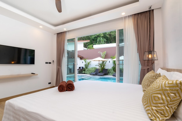 Spacious bedroom pool access with sliding door overlooking to garden with sun bed and umbrella