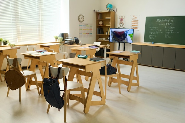 Spacious classroom of biology or anatomy with several wooden desks with chairs