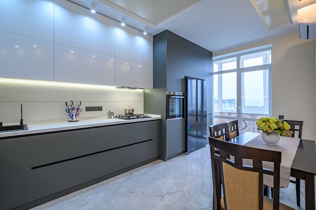 Spacious luxury white and dark grey modern kitchen interior with dining table