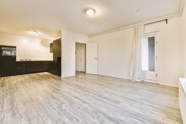 A spacious room with laminate floors and a corner kitchen in black colors in a modern house