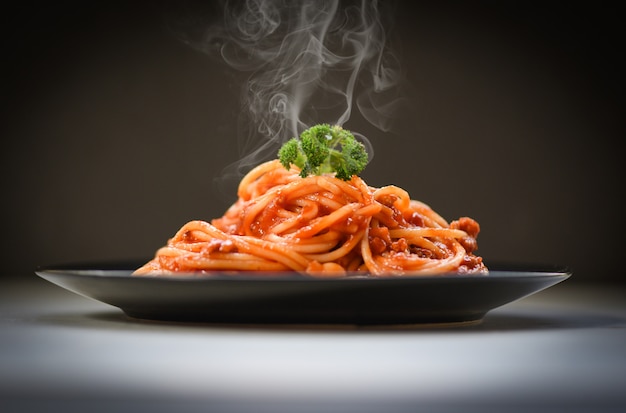 Spaghetti bolognese on black background / Spaghetti italian pasta served on black plate with tomato sauce and parsley in the restaurant italian food and menu