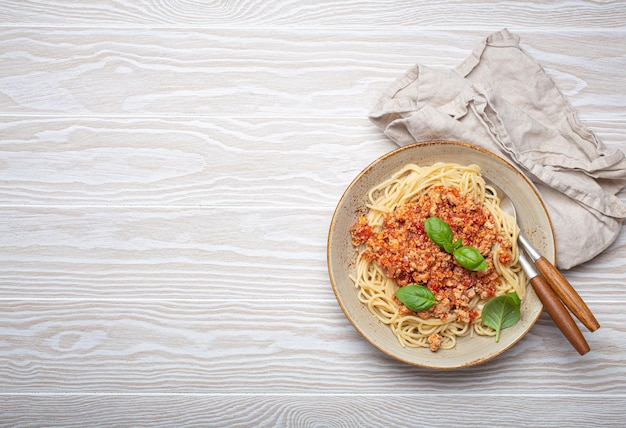 Photo spaghetti bolognese with basil garnish on white wooden table