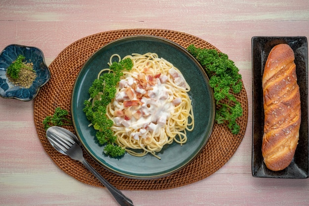 Spaghetti carbonara with Ham and Bacon on green plate on wooden table