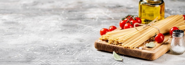 Spaghetti dry on a wooden cutting board with tomatoes