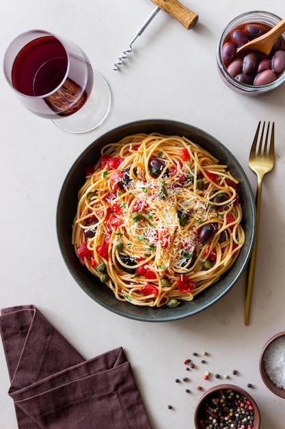 Spaghetti pasta Alla Puttanesca with capers Kalamata olives cheese tomatoes and anchovies Italian food