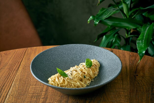 Spaghetti pasta cacho pepe in a gray plate on a wooden background. Creamy pasta