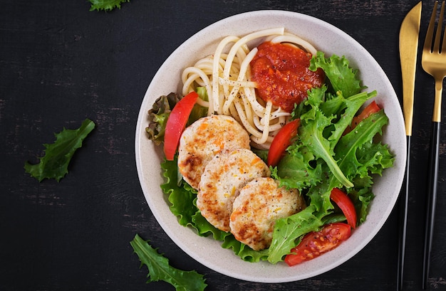 Spaghetti pasta chicken burgers and salad in bowl Chicken patties Lunch Top view above copy space