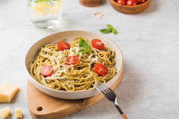 Spaghetti pasta with pesto sauce parmesan cheese and cherry tomatoes on a plate Menu Italian cuisine Copy space