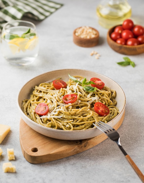 Spaghetti pasta with pesto sauce parmesan cheese and cherry tomatoes on a plate Menu Italian cuisine