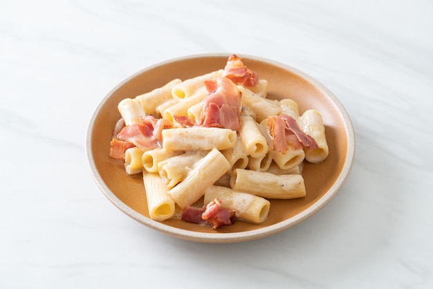 Spaghetti rigatoni pasta with white sauce and bacon