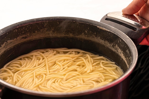 Spaghetti in a saucepan in the hands of a cook