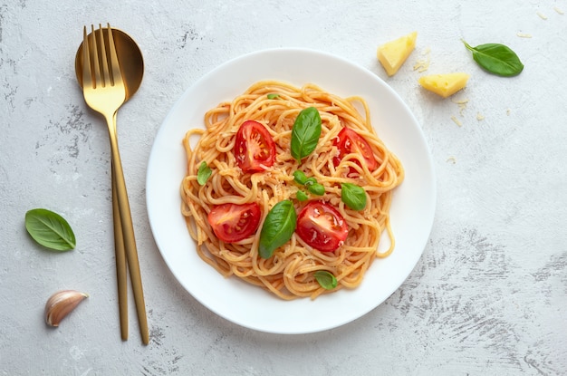 Spaghetti in tomato sauce with cheese on a white plate on a light space