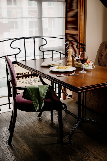 Spaghetti with cheese and egg on a white plate on wooden surface