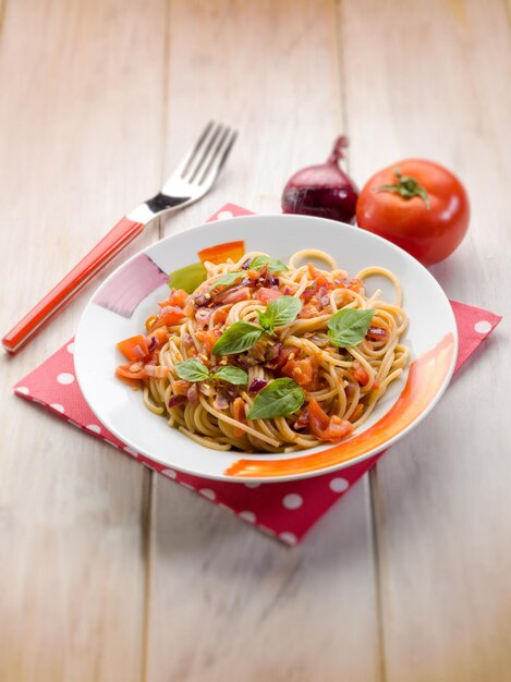 Spaghetti with fresh tomato red onion and hot chili pepper selective focus