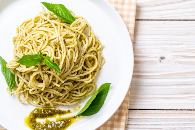 spaghetti with pesto sauce, olive oil and basil leaves.