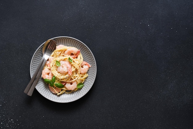 Spaghetti with shrimps, bÃ©chamel sauce and parmesan on a concrete black background. View from above. Menu. Recipe.