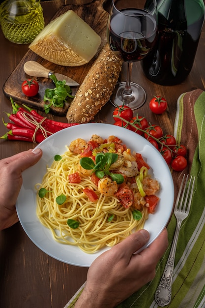 Spaghetti with shrimps, cherry tomatoes and spices on wooden background.