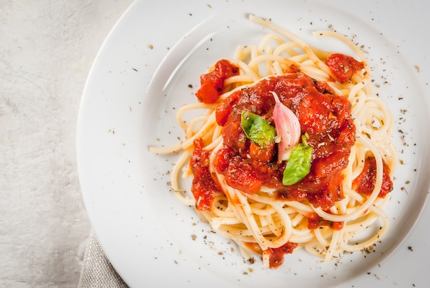 spaghetti with tomato marinara sauce and basil on a white concrete table