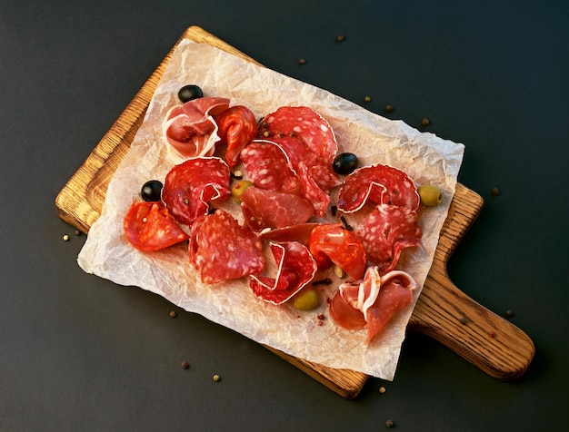 Spanish cold meat assortment Chorizo fuet LOMO jamon Iberico olives Black background Top view