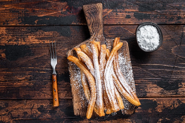 Spanish dessert churros with sugar powder on a wooden tray